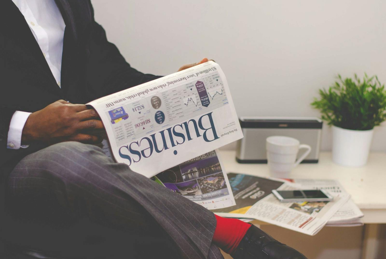 Businessman reading a financial newspaper at a desk, highlighting finance and commerce theme.